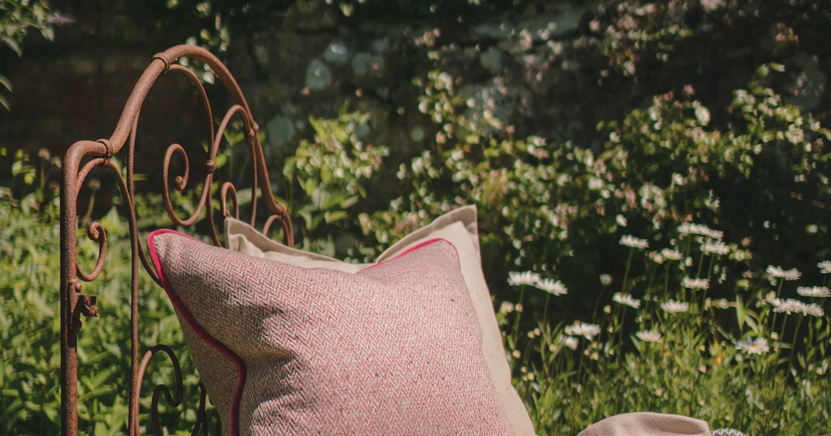 Luxury cushions and throws displayed on outdoor furniture in the sun