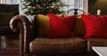 Festive home setting displaying red oxford cushions on a sofa. 