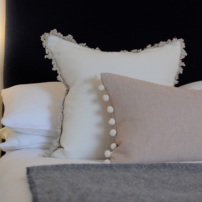 Luxury fringed cushion and pompom pillow as bedroom accessories.